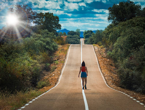 istock Woman alone on beautiful empty country bend, asphalt road. 1371095555