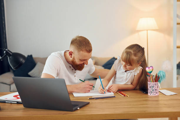 istock Using laptop. Father with his little daughter is at home together 1371096830