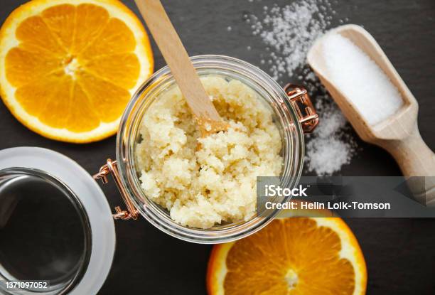 Homemade Sugar Body Scrub In Glass Jar With Fresh Orange Slices And Wooden Spoon With Sugar Powder On Black Stone Cutting Board Body Skin Care Concept Stock Photo - Download Image Now