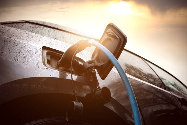 A detailed closeup view of a car currently being charged at an electric charging station, showcasing the connection of the charging cable