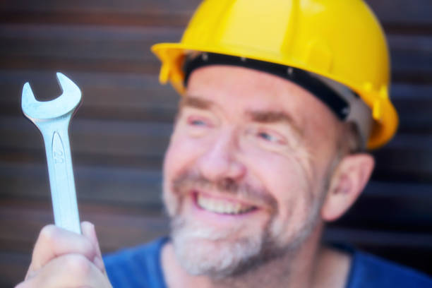 Handyman with yellow hard hat and metal wrench