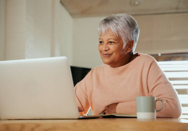 istock Elderly multi-ethnic female sitting at home counter using laptop, smiling 1371101665