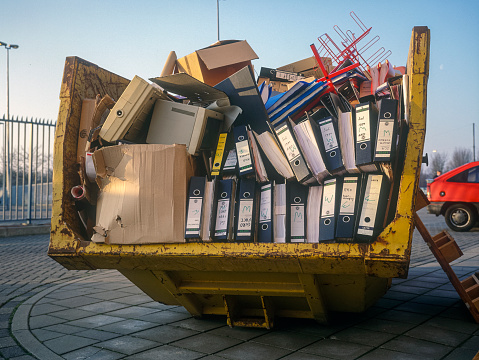 Dumpster with office suplies and old file folders and old monitors. The Netherlands.