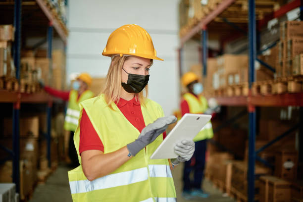 istock Caucasian female worker checking the order inside a warehouse while wearing a face mask - Face focus 1371101933