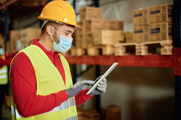 istock Caucasian worker man using tablet inside warehouse while wearing safety mask - Focus on face 1371102483