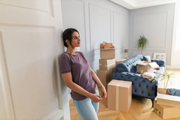 Beautiful woman stands in her new apartment proudly looking around and thinking about how to decorate it while moving in. Beautiful woman stands in her new apartment proudly looking around and thinking about how to decorate it while moving in. looking around stock pictures, royalty-free photos & images