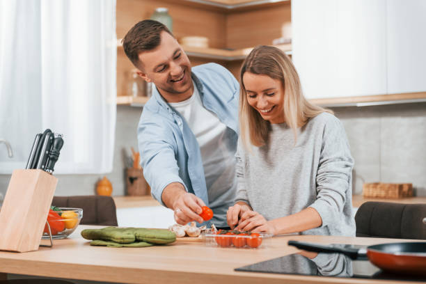 istock Helping each other. Couple preparing food at home on the modern kitchen 1371107564