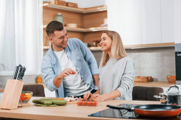 istock Helping each other. Couple preparing food at home on the modern kitchen 1371107582