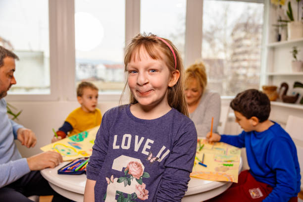 Portrait of confident girl with cleft lip, with her family behind her Portrait of girl with cleft lip, with her family behind her cleft lip stock pictures, royalty-free photos & images