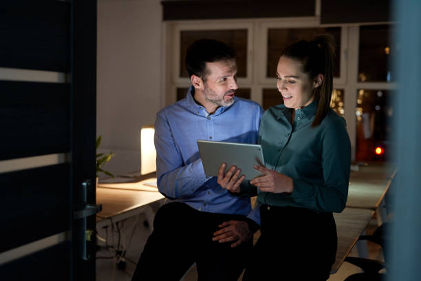 Caucasian woman and man working late together at the office stock photo