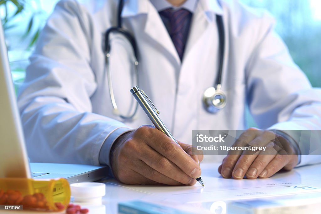 Doctor writing prescription or medical notes Doctor writing prescription or medical notes  Computer Stock Photo