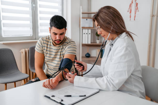 lekarz mierzący ciśnienie krwi młodego pacjenta - doctor patient doctors office teenager zdjęcia i obrazy z banku zdjęć