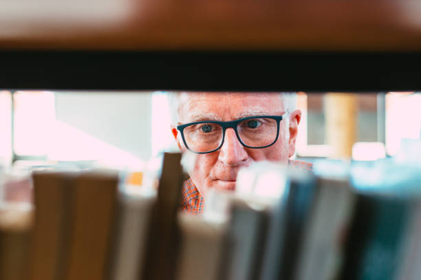 istock Senior man looking at books on shelf in library 1371121517