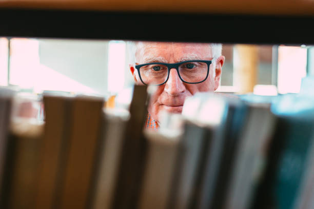 istock Senior man looking at books on shelf in library 1371121525
