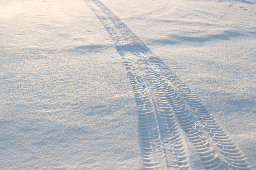 Tire tracks in fresh white snow surface. Wintertime background with copy space