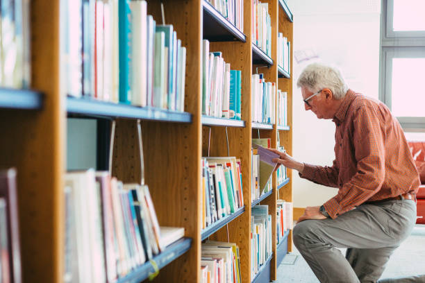 istock Senior man looking at books on shelf in library 1371126004