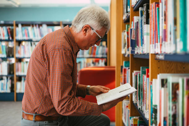 istock Senior man looking at books on shelf in library 1371126058