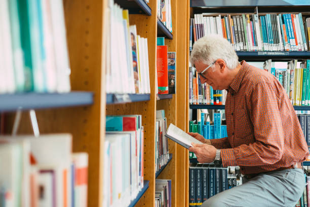istock Senior man looking at books on shelf in library 1371126086