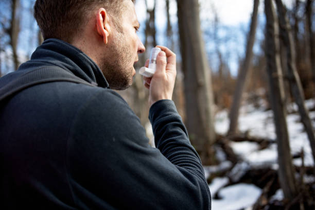 Mid adult man using asthma inhaler during a hike Mid adult man using asthma inhaler during a hike asthma travel stock pictures, royalty-free photos & images