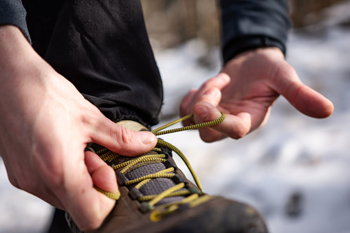 Caucasian man stop hiking to tie shoe. Close-up
