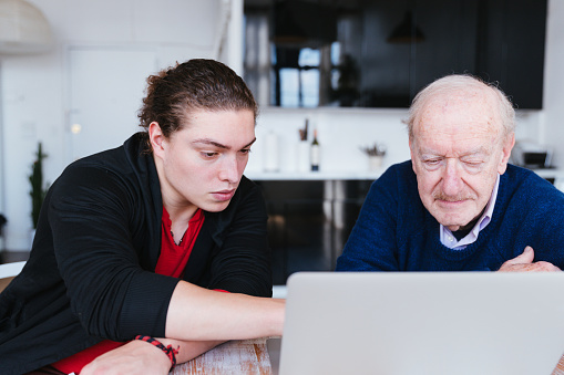Grandson teaching his grandfather how to use laptop
