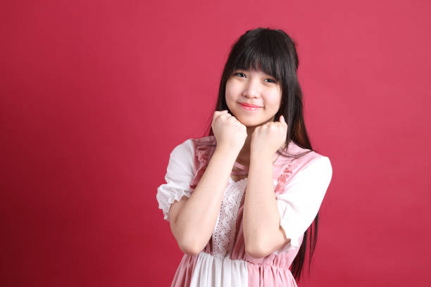 The teen Asian girl with cute Japanese costume standing on the red background.