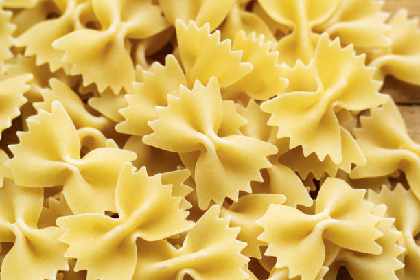 sterta surowego farfalle włoskiego makaronu - bow tie pasta italian cuisine bow heap zdjęcia i obrazy z banku zdjęć