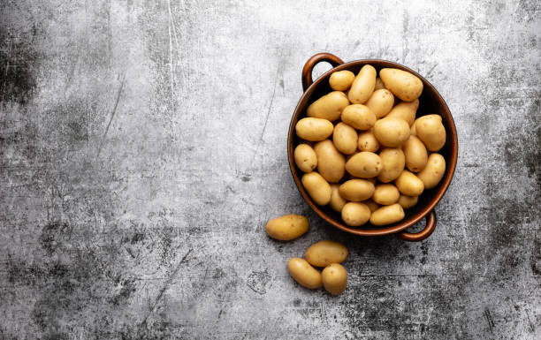 istock Raw small potatoes in a cast iron skillet on a beton background. 1371129627