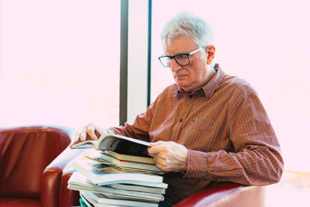 istock Senior man with stack of books in library 1371131873