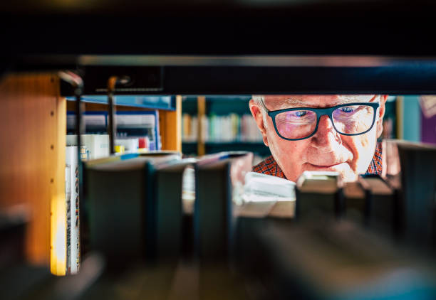 istock Senior man looking at books on shelf in library 1371133559