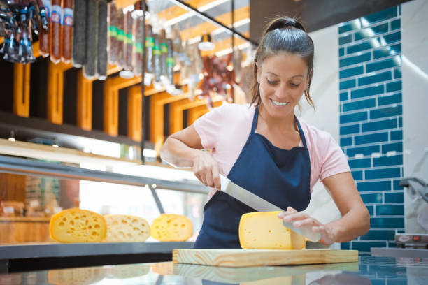 istock Saleswoman cutting cheese at kitchen counter 1371133602