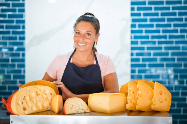 istock Smiling female owner with various cheese at shop 1371134996