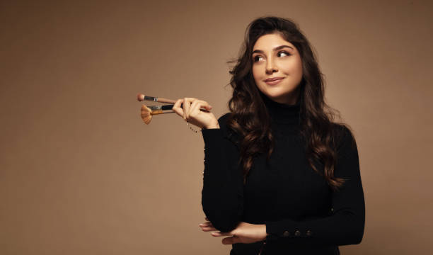 Portrait of cute beautiful young woman holding makeup brushes. Portrait of cute beautiful young woman holding makeup brushes. makeup artist stock pictures, royalty-free photos & images
