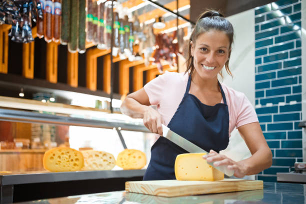 Smiling owner cutting fresh cheese on counter