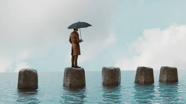 istock Man holds umbrella while standing on a rock in the sea 1371136184