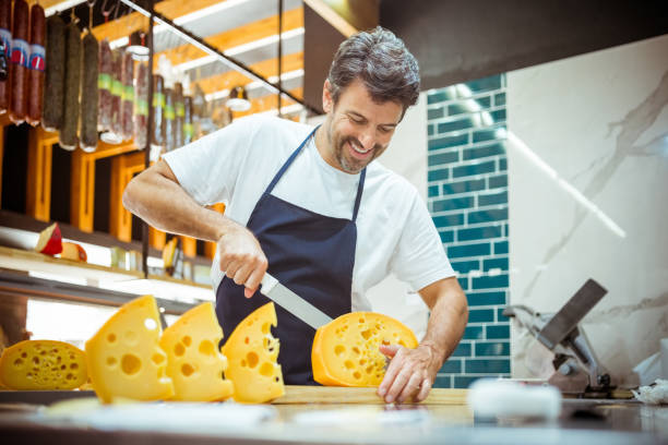 istock Smiling male owner cutting cheese on counter 1371137519