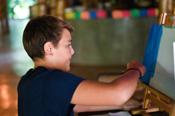 istock Teen Latinx boy at an art class or studio using paint on a canvas to create art 1371140852