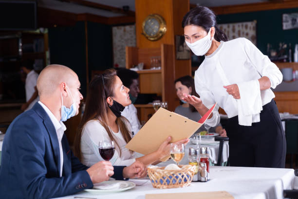 istock Waitress in protective mask helping couple in choosing meals 1371141026