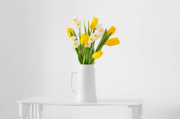 istock white and yellow spring flowers  in vase on white background 1371141568