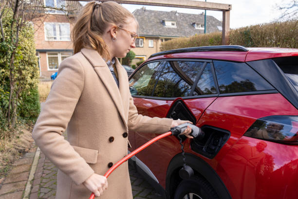jeune femme rechargeant une voiture électrique - electrical conduit photos et images de collection