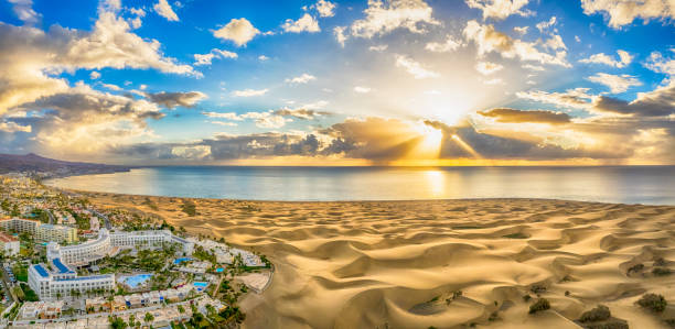 Landscape with Maspalomas sand dunes at sunrise, Gran Canaria Landscape with Maspalomas town and golden sand dunes at sunrise, Gran Canaria, Canary Islands, Spain grand canary stock pictures, royalty-free photos & images