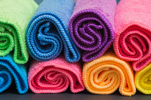 Colorful rolled up microfibre cleaning cloths arranged in a rows.