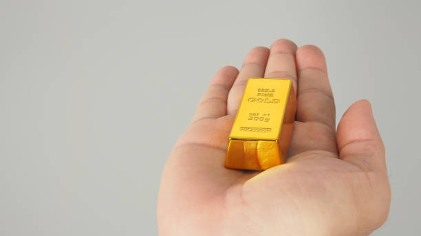 istock Gold bar in hand palm isolated on grey background. 1371148752