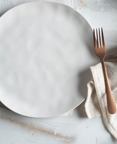 Empty white ceramic plate, fork, and a napkin viewed from a high angle view shot.Cera