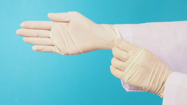 istock Side view. The doctor's hand is pulling white latex gloves isolated on blue background. 1371149824