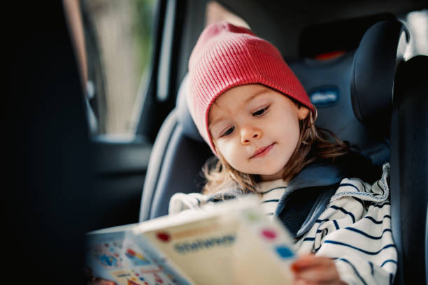 Cute Little Girl Reading Book While Traveling by Car stock photo