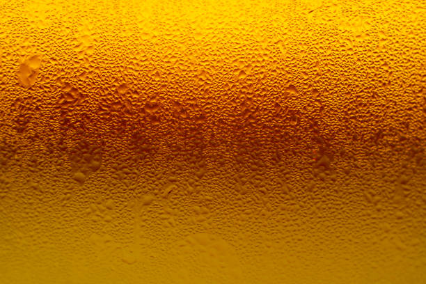 текстура капель воды на градиентной золотисто-желтой лагерной пивной стеклянной бутылке - amber beer стоковые фото и изображения
