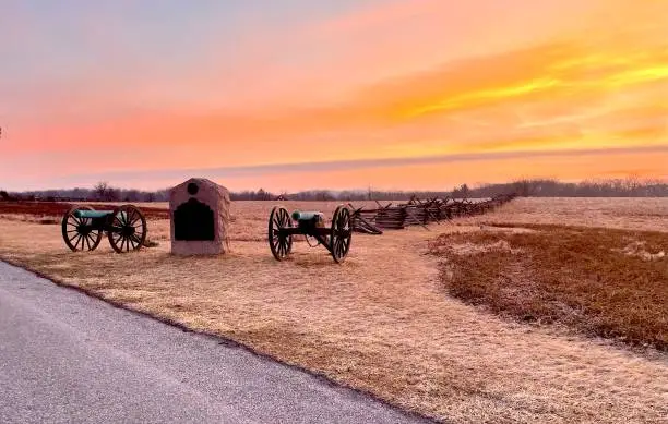 Battlefield on a cold morning with sun rising behind cannons.