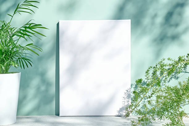 istock Blank white drawing canvas on mint colored surface with palm in white pot, home plants and soft floral shadows. Spring Summer Typography, To do list. Ecodesign. 1371155990