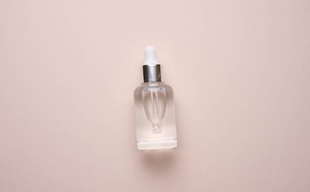 istock glass transparent white bottle with a pipette. Container for cosmetics, acids and oils on a beige background 1371159194
